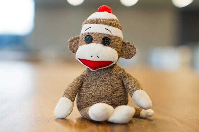 monkey plush toy with hat sitting on wooden surface