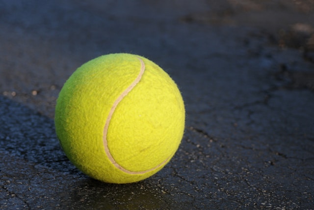 green tennis ball on a grey concrete floor